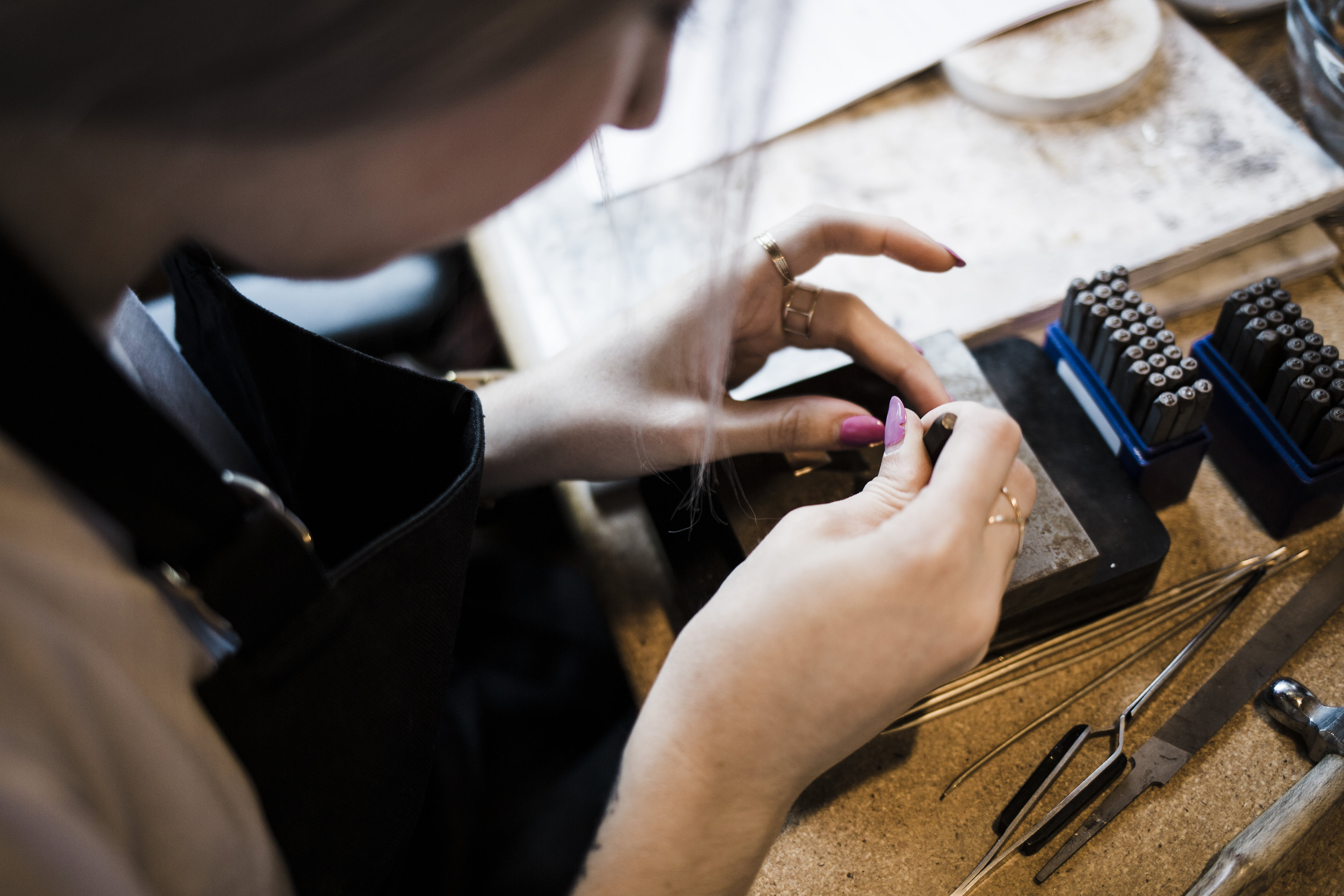 Person working on jewelry with tools on a table.