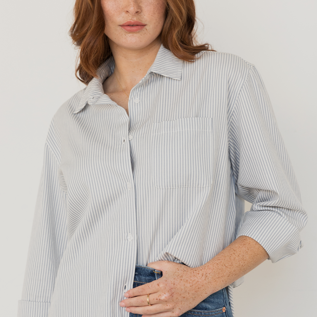 Person wearing a striped shirt and jeans against a plain background.