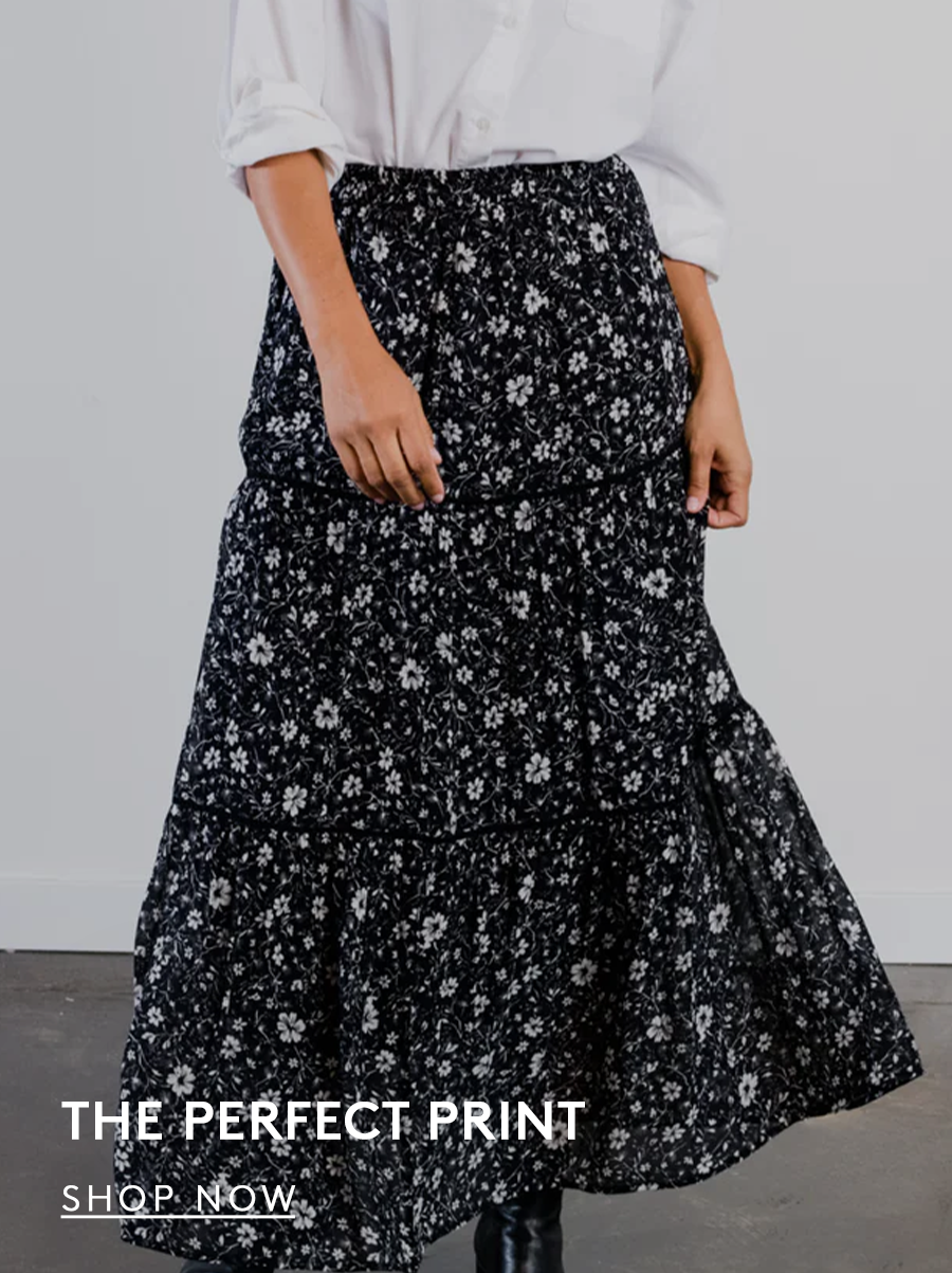 Woman wearing a black and white floral printed tiered skirt. text reads the perfect print. shop now button.