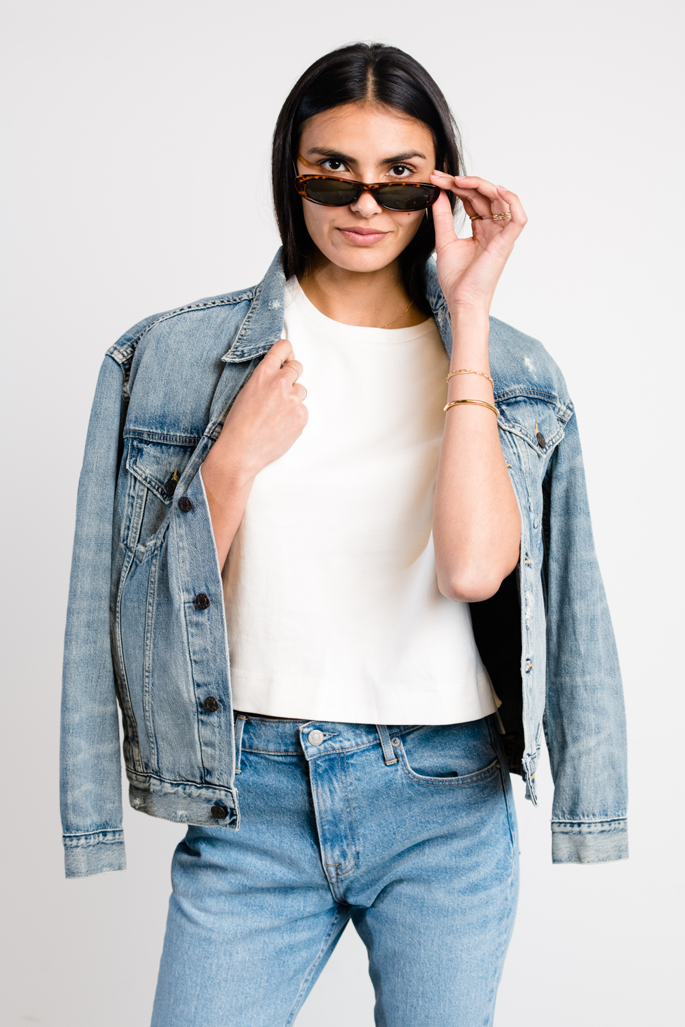 Person wearing denim jacket and sunglasses, posing confidently.