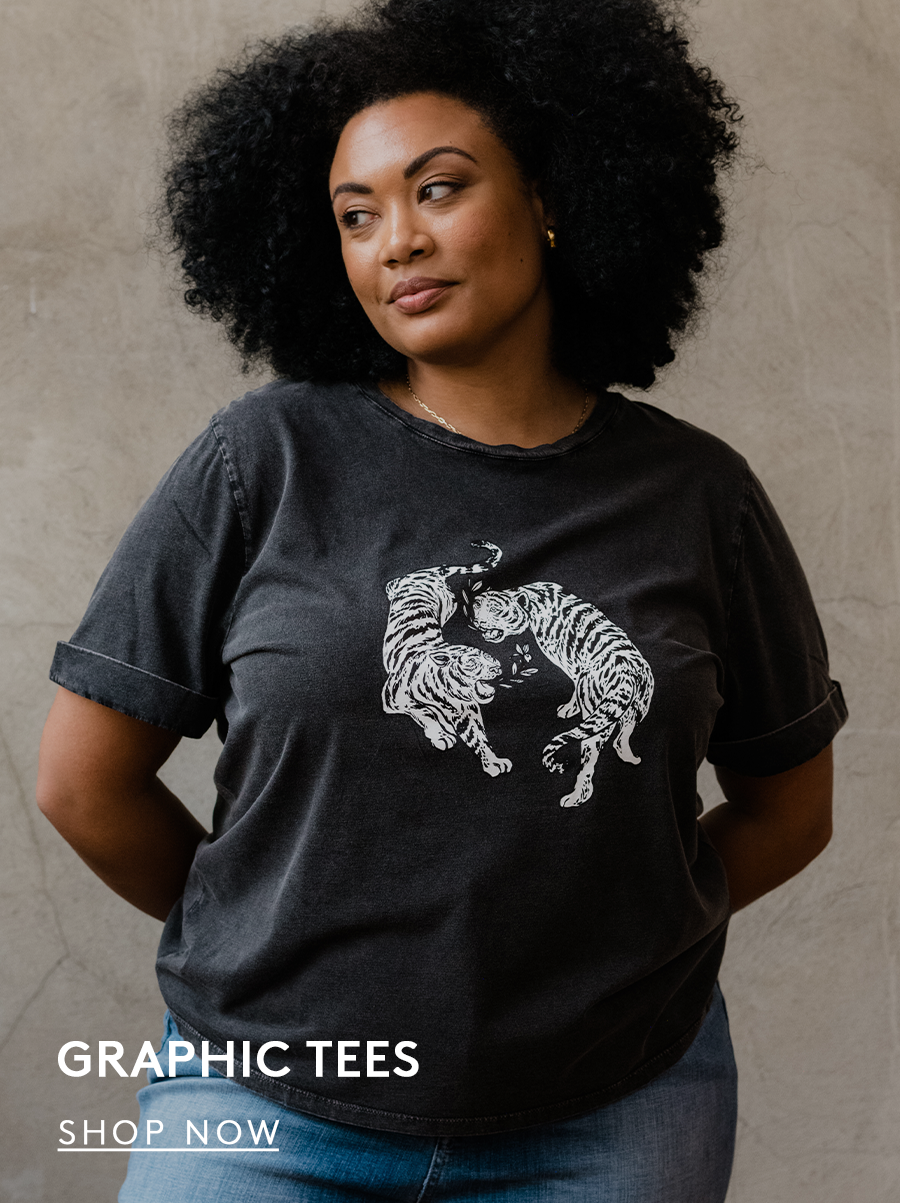 Woman wearing a washed black graphic tee with two tigers and iris as the design. text reads graphic tees. shop now button.