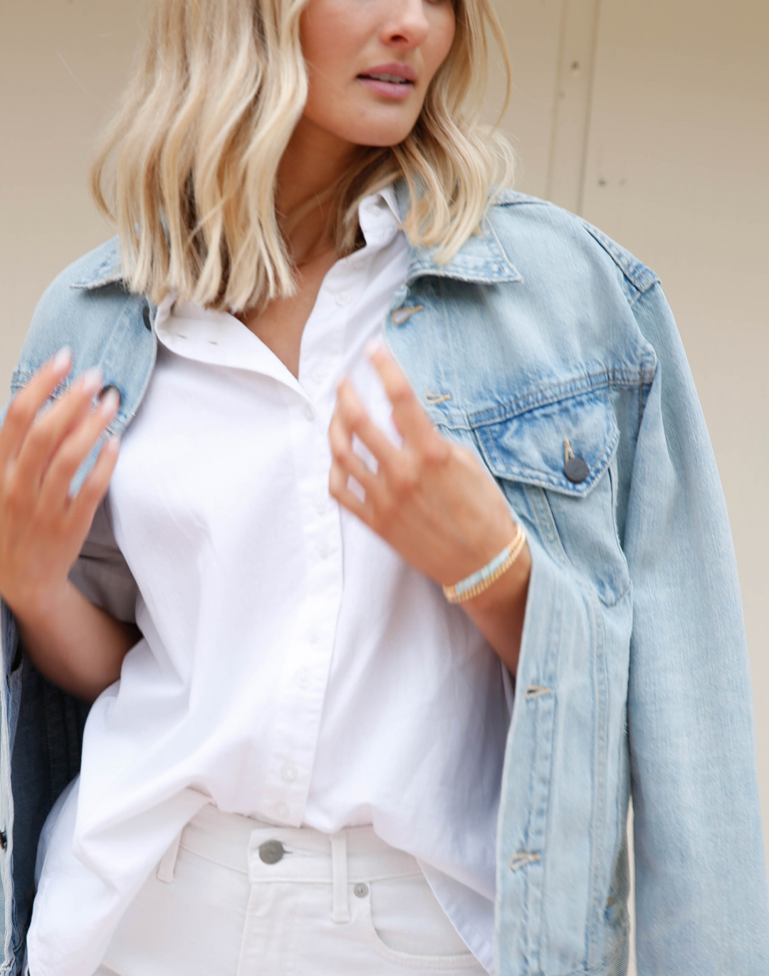 Person wearing a denim jacket over a white shirt.