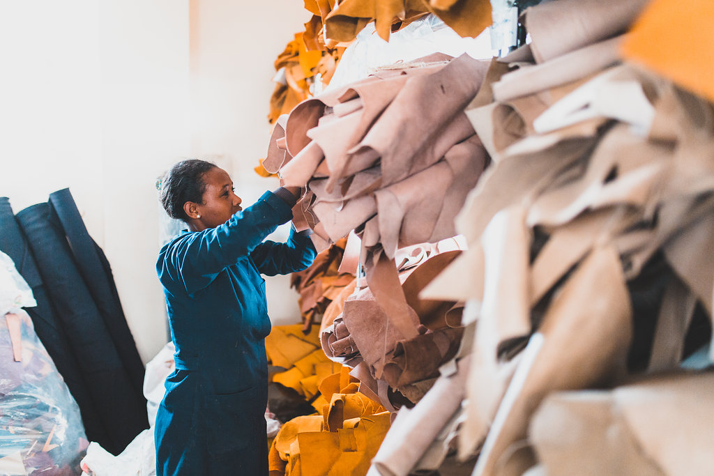 Two women working with orange fabric in a workshop.