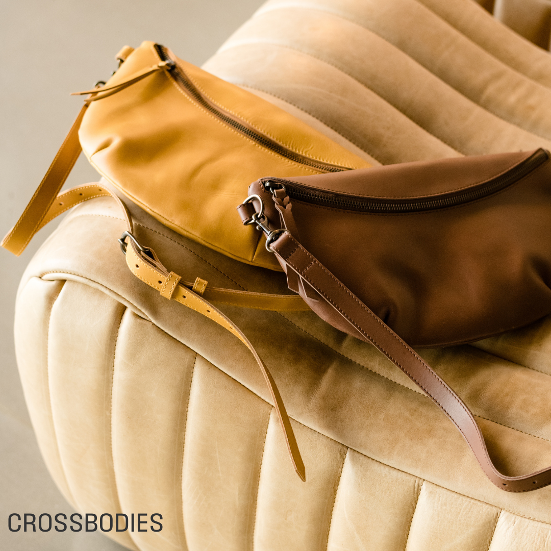 Two crossbody bags on a beige quilted surface. SHOP CROSSBODIES