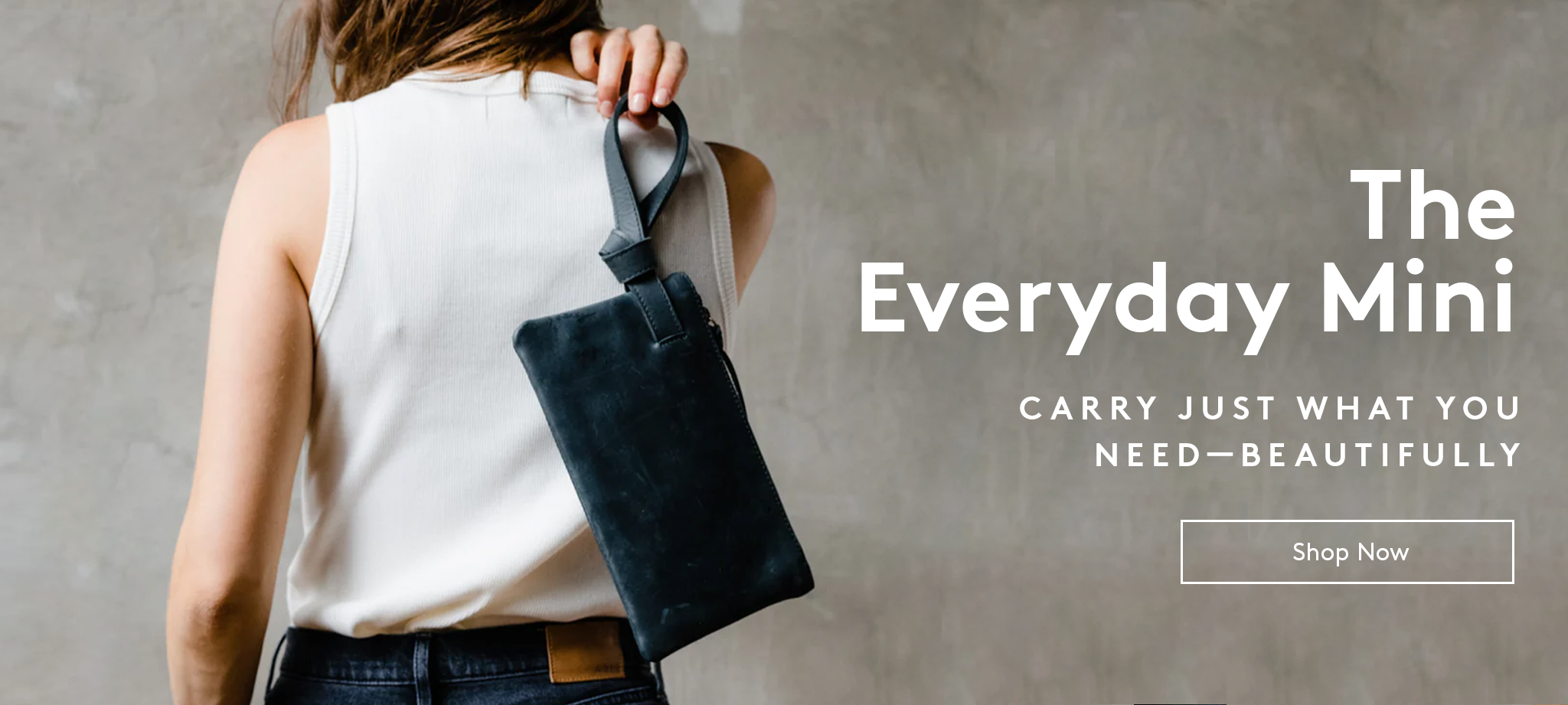 Person holding a black leather wristlet text reads 'The Everyday Mini.' carry just what you need - beautifully. shop now button.