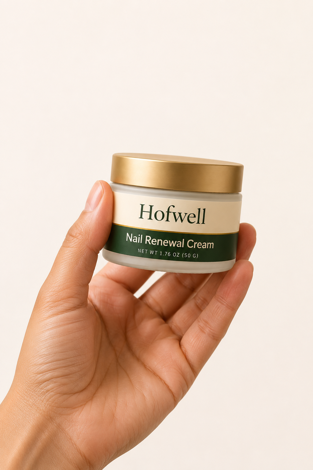 A hand holding a jar of Hofwell Nail Renewal Cream against a plain background.