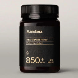Dark jar labeled 'Manukora Raw Mānuka Honey' with 850+ MGO, made in New Zealand.