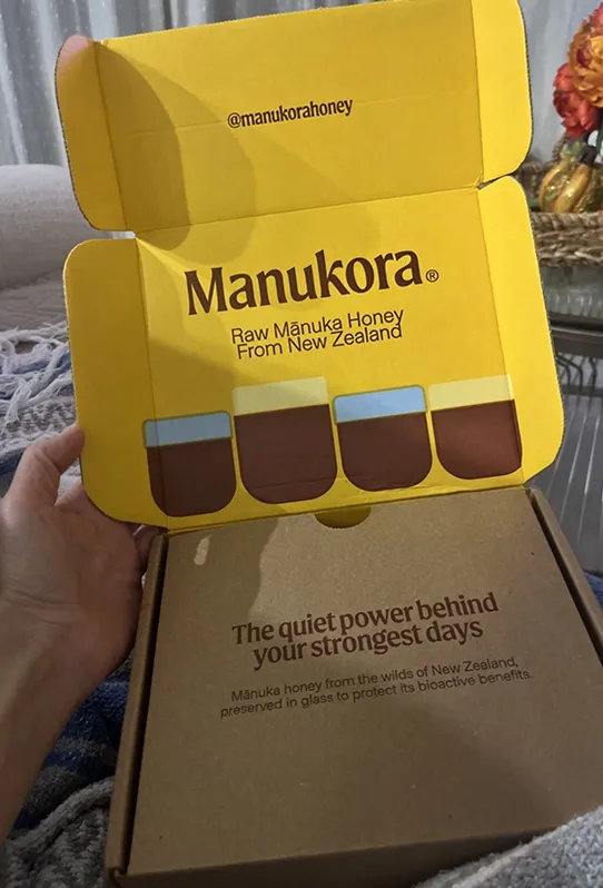 Opened Manukora honey box showing packaging and text.