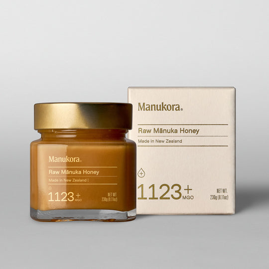 Jar and box of Manukora Raw Mānuka Honey with gold lid.