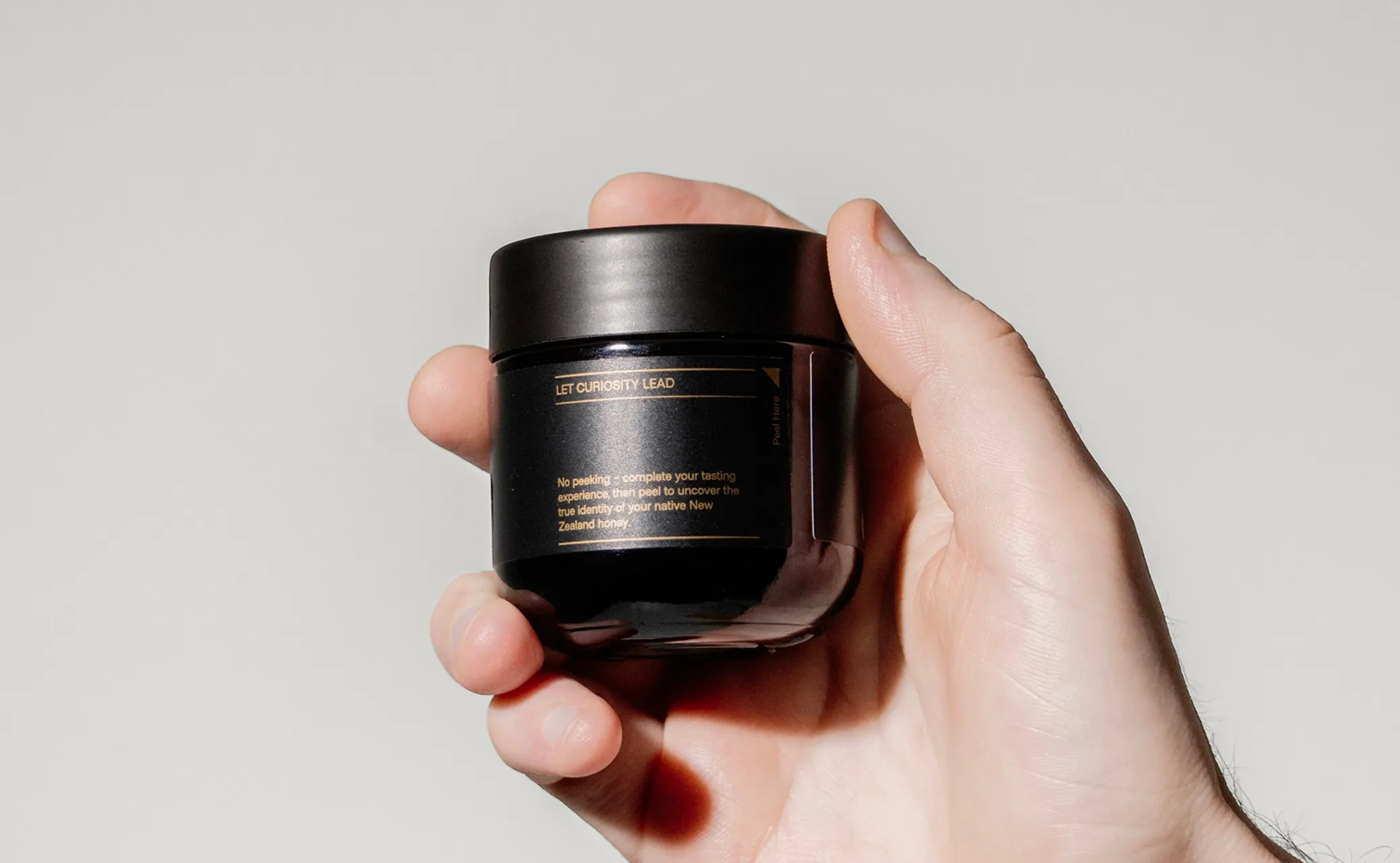 Hand holding a black jar with a label.