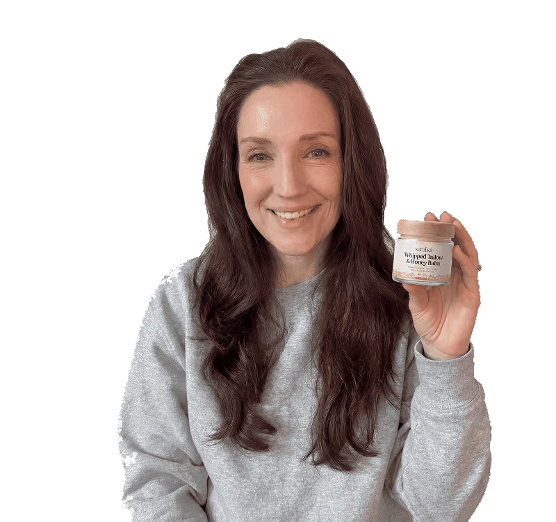 A smiling woman with long brown hair holds up a small jar of Serabel Whipped Tallow & Honey Balm.