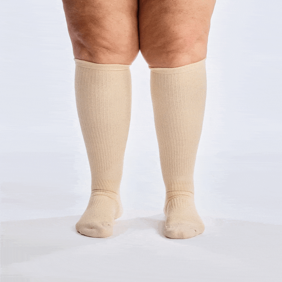 Person wearing beige knee-high socks on a white background.