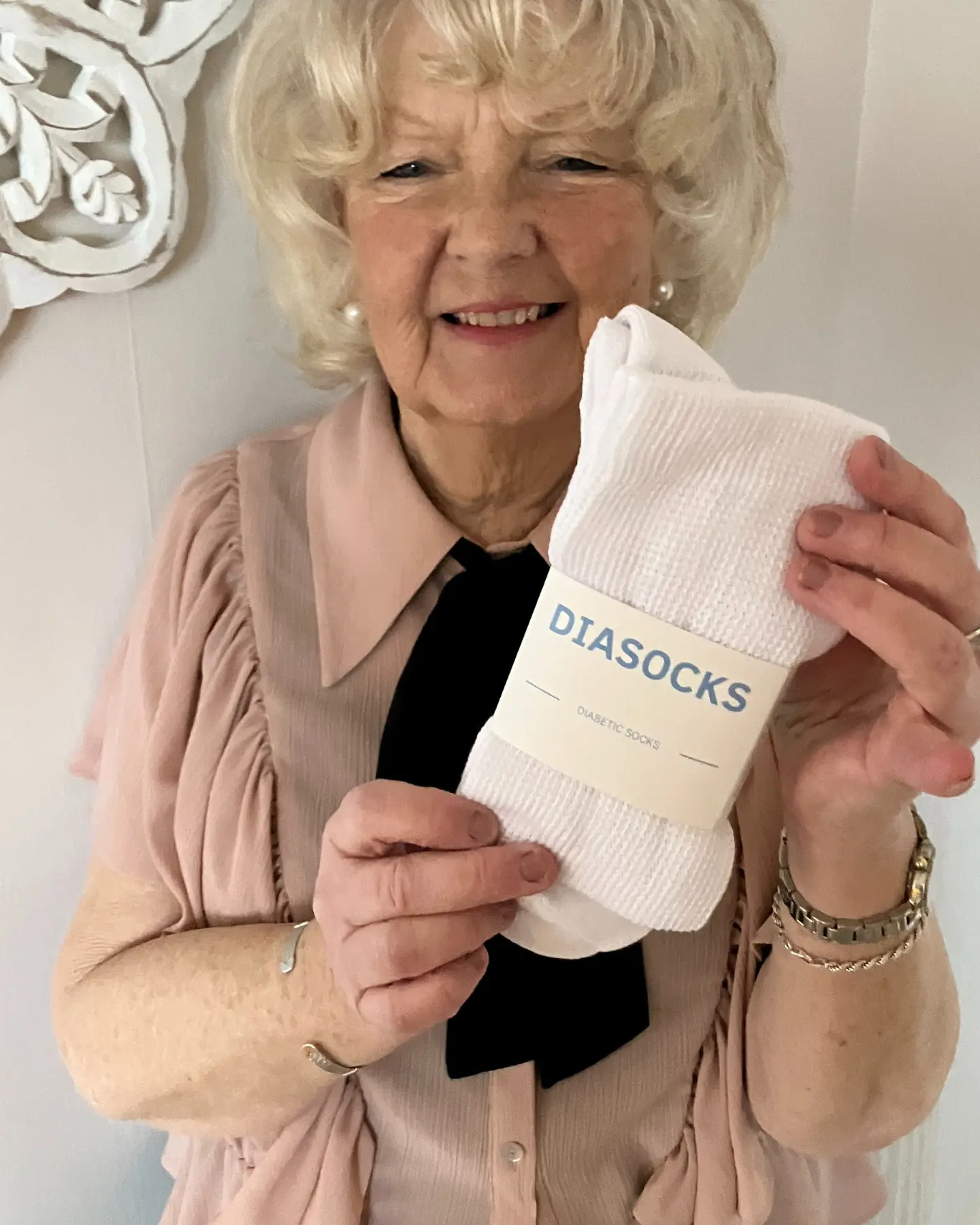 Person holding a pair of white socks labeled 'DIASOCKS'.