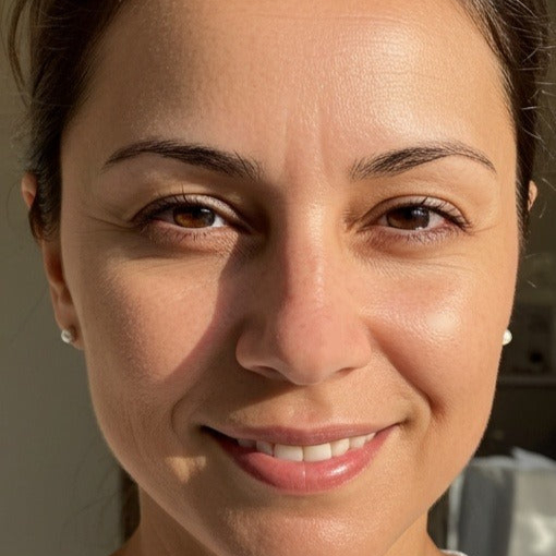 Close-up of a smiling person with brown eyes and earrings.