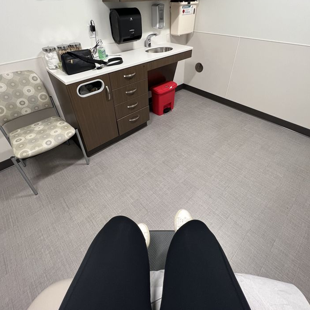 A first-person perspective of a person sitting on an examination table in a doctor's office.
