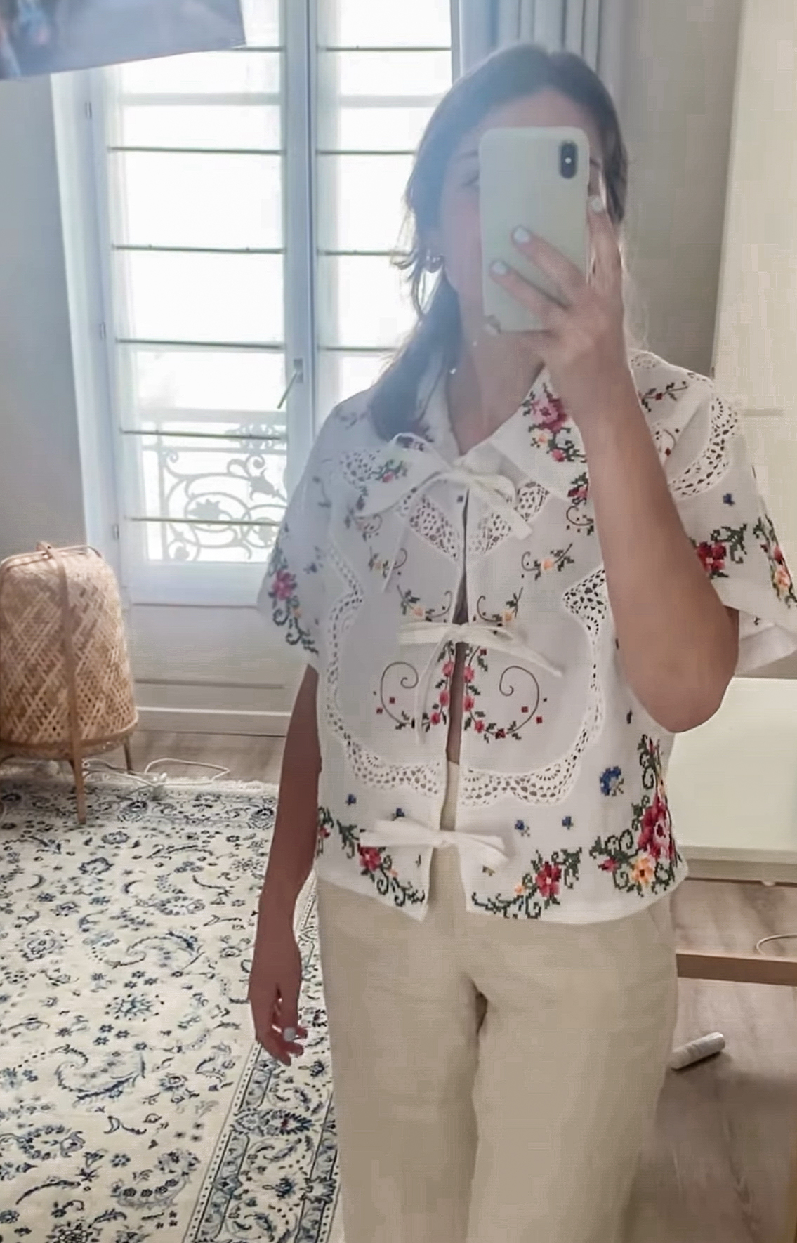 Person taking a mirror selfie wearing a floral embroidered top.