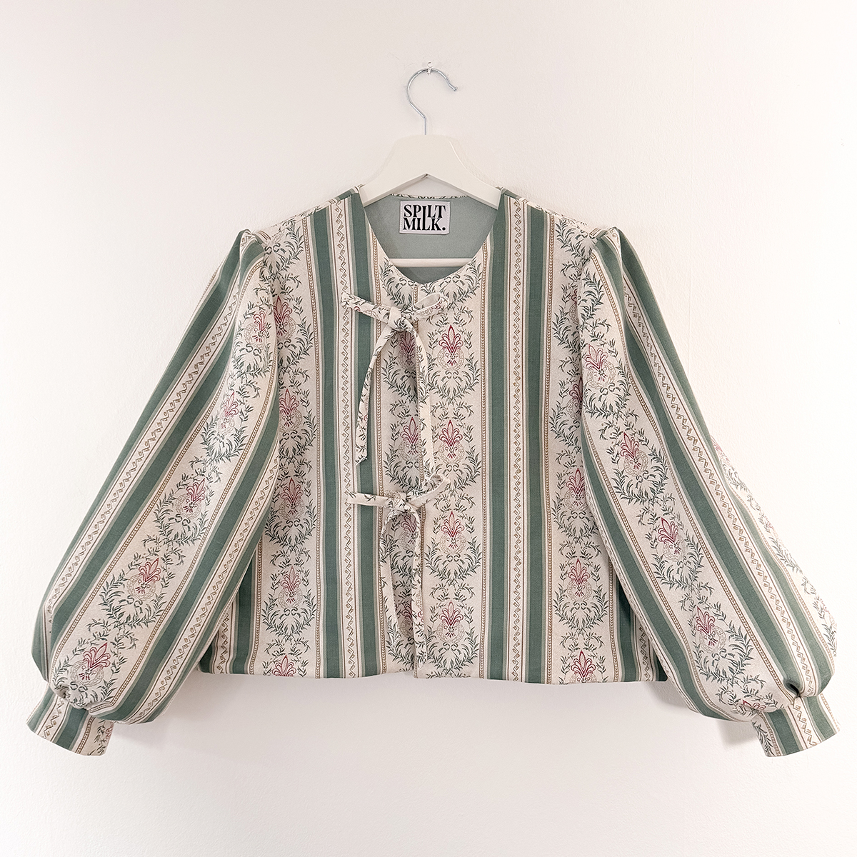 Striped floral jacket with long puffy sleeves, hung on a white hanger.
