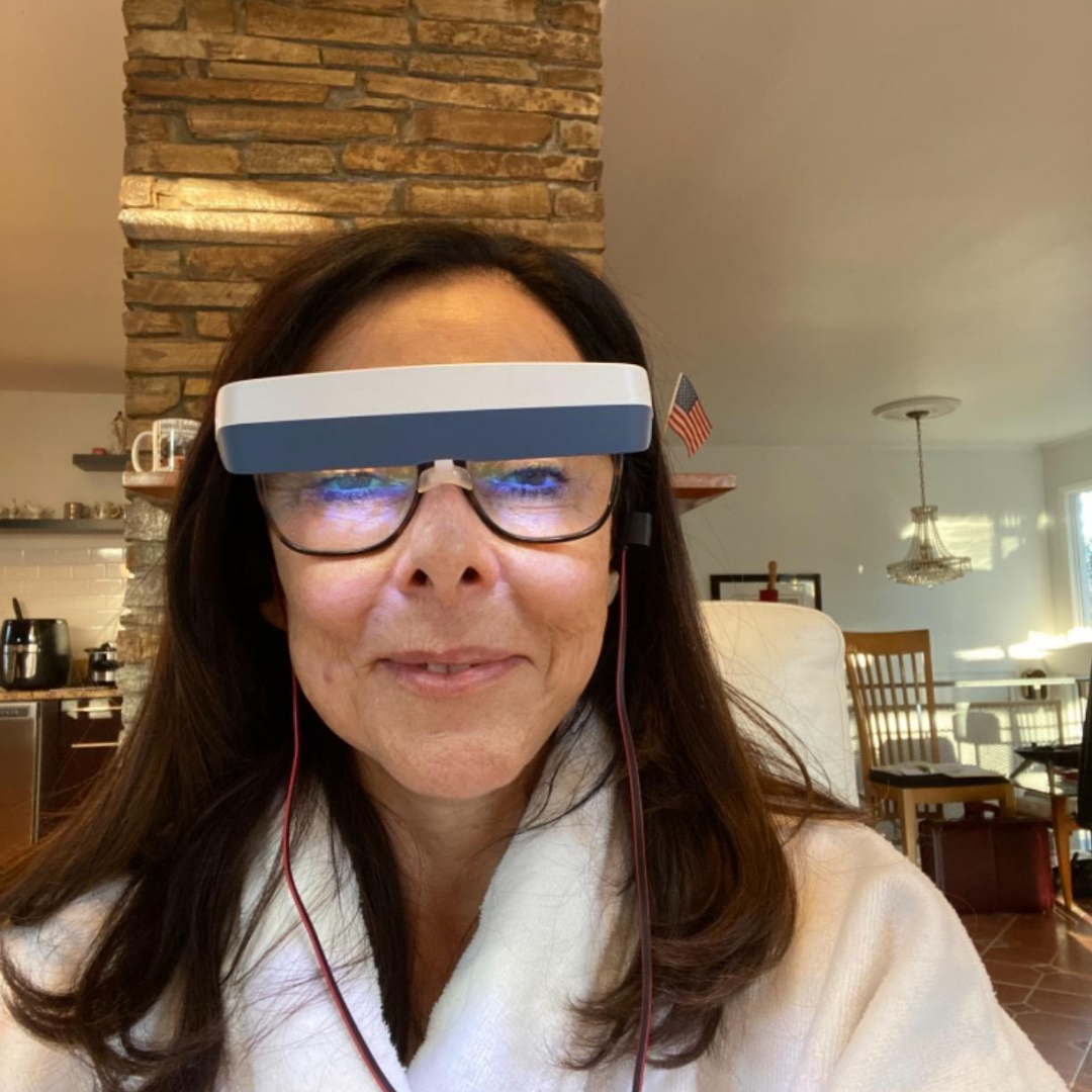Person wearing electronic glasses in a cozy room with wooden furniture.