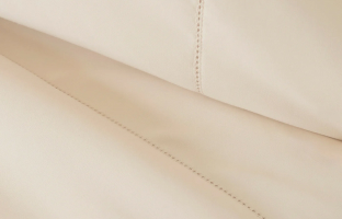 A close-up shot of folded, off-white fabric with a line of decorative stitching.