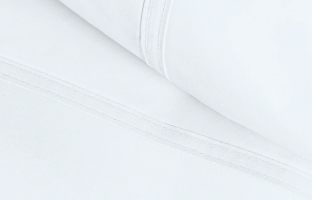A close-up of a folded white fabric sheet, showing the stitched hem and seams.
