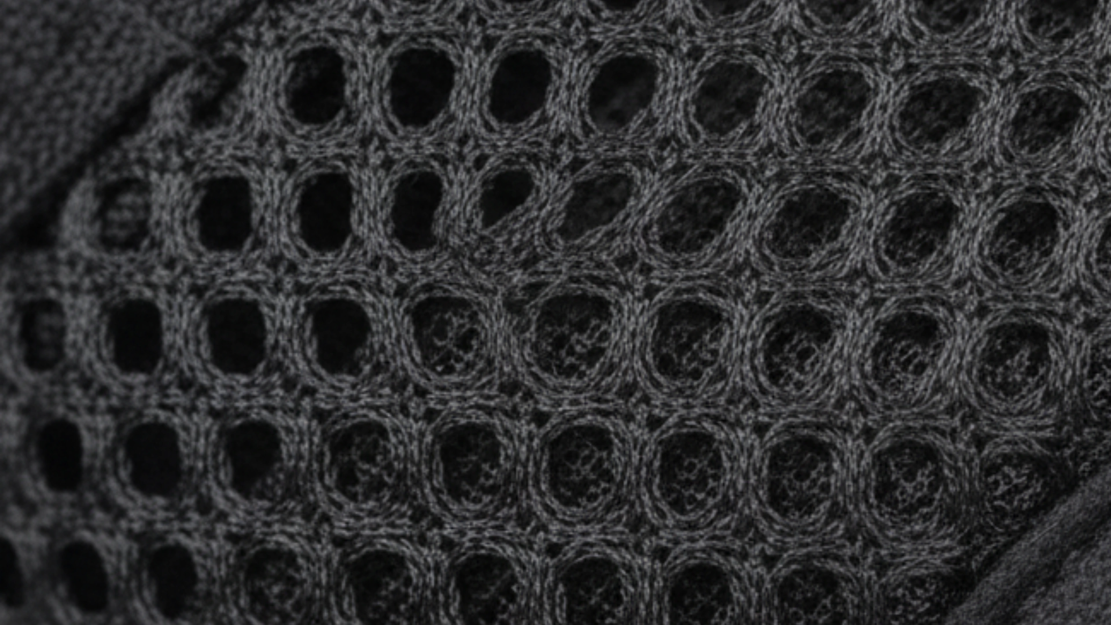 Close-up of a textured, black mesh fabric with circular patterns.