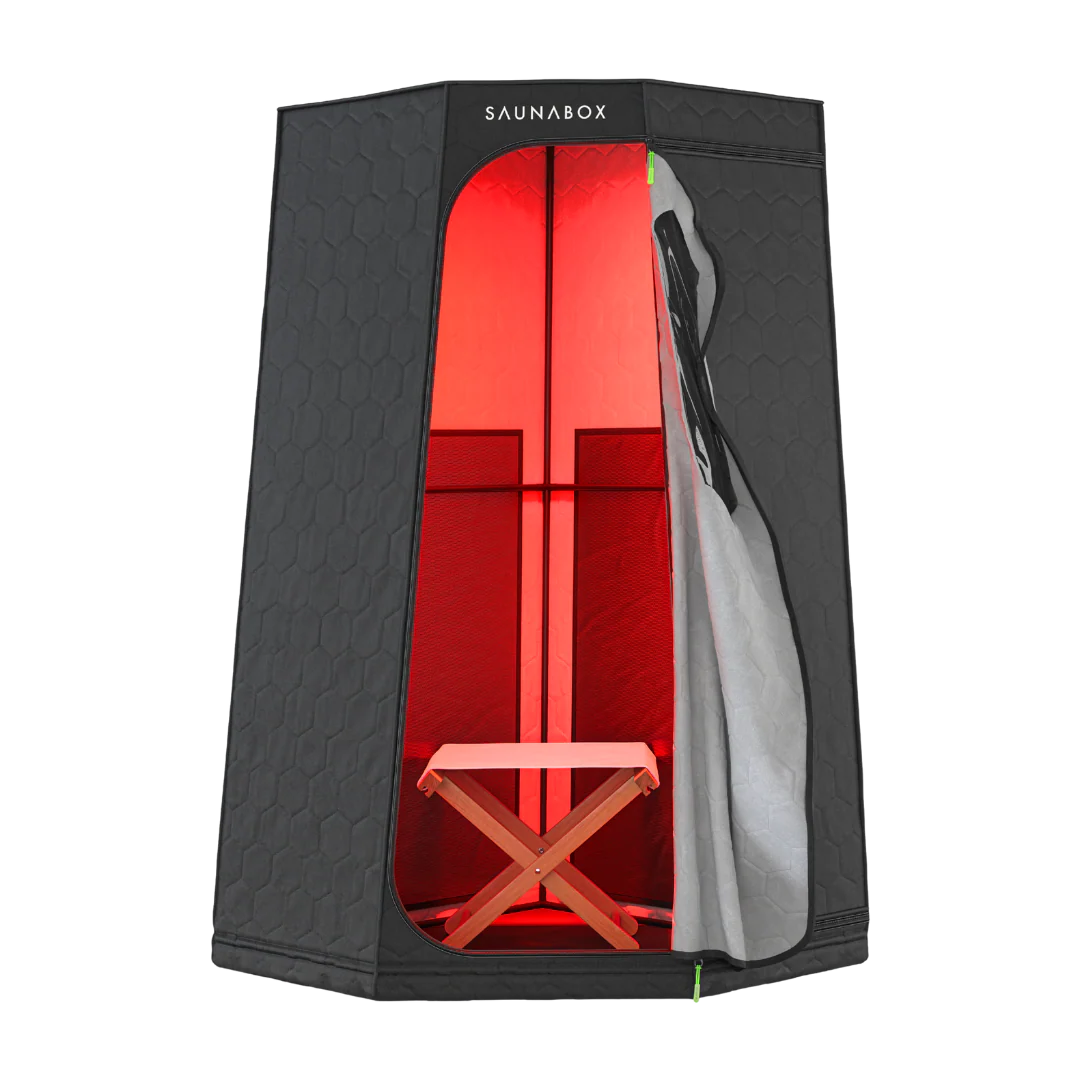 Portable sauna with black exterior, glowing red interior, and a folding wooden chair inside.