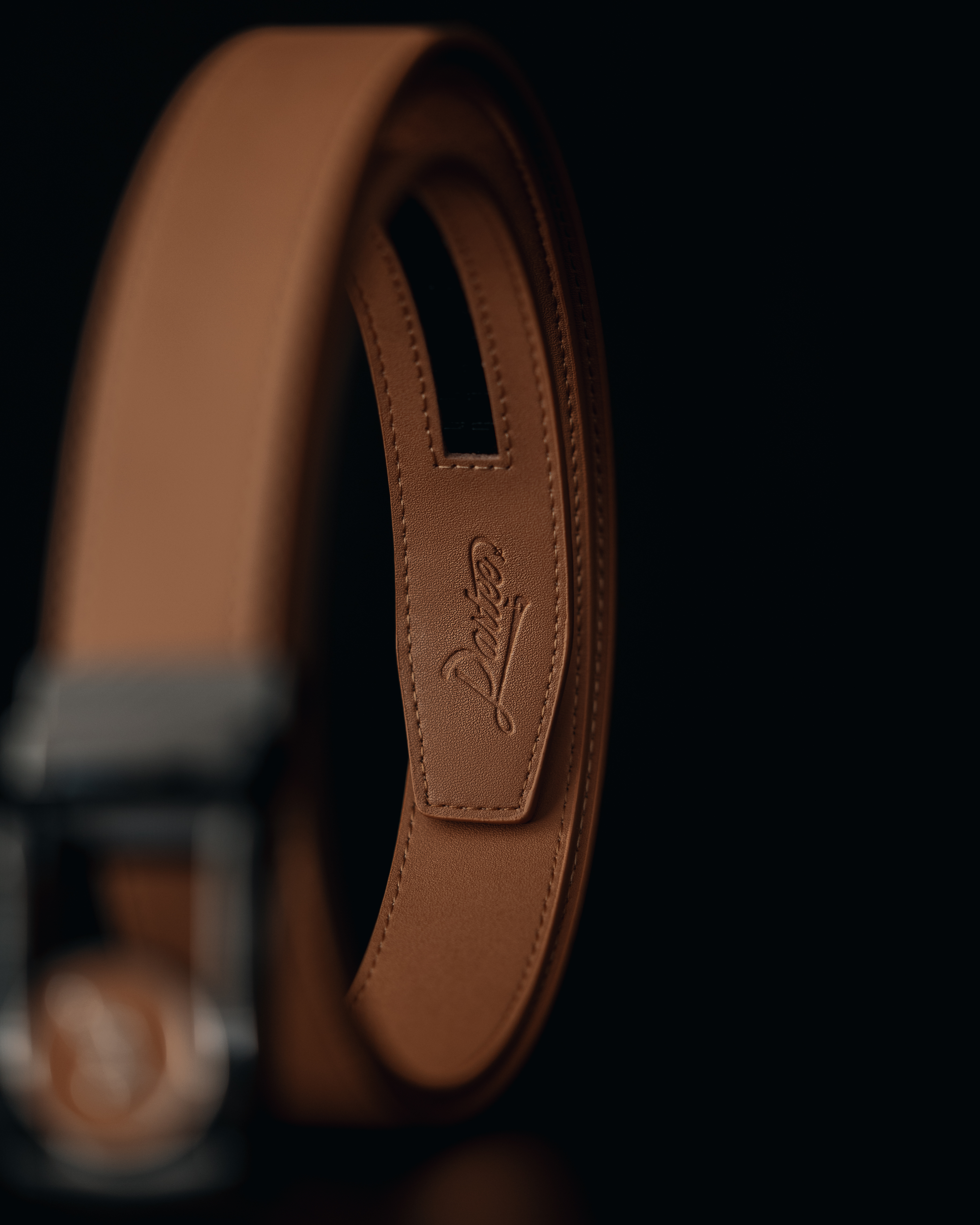 Close-up of a brown leather belt with a textured finish on a dark background.