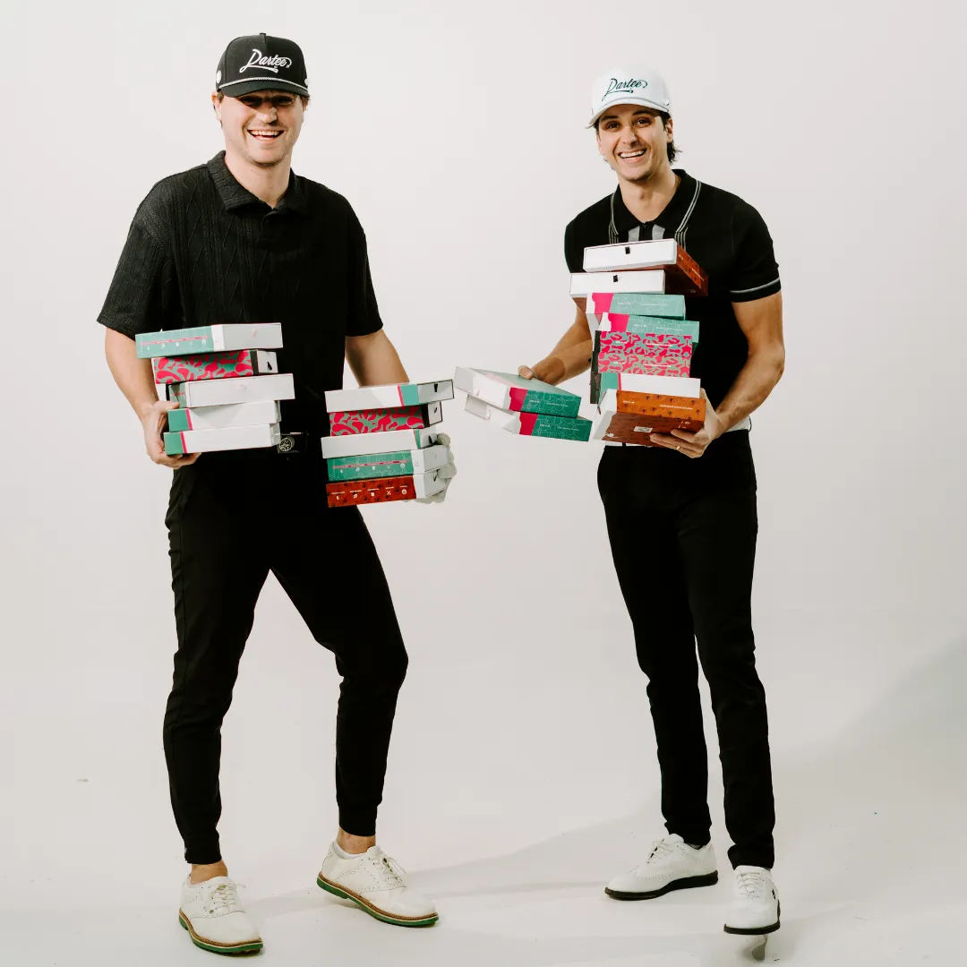 Two people holding stacks of colorful shoe boxes, smiling.