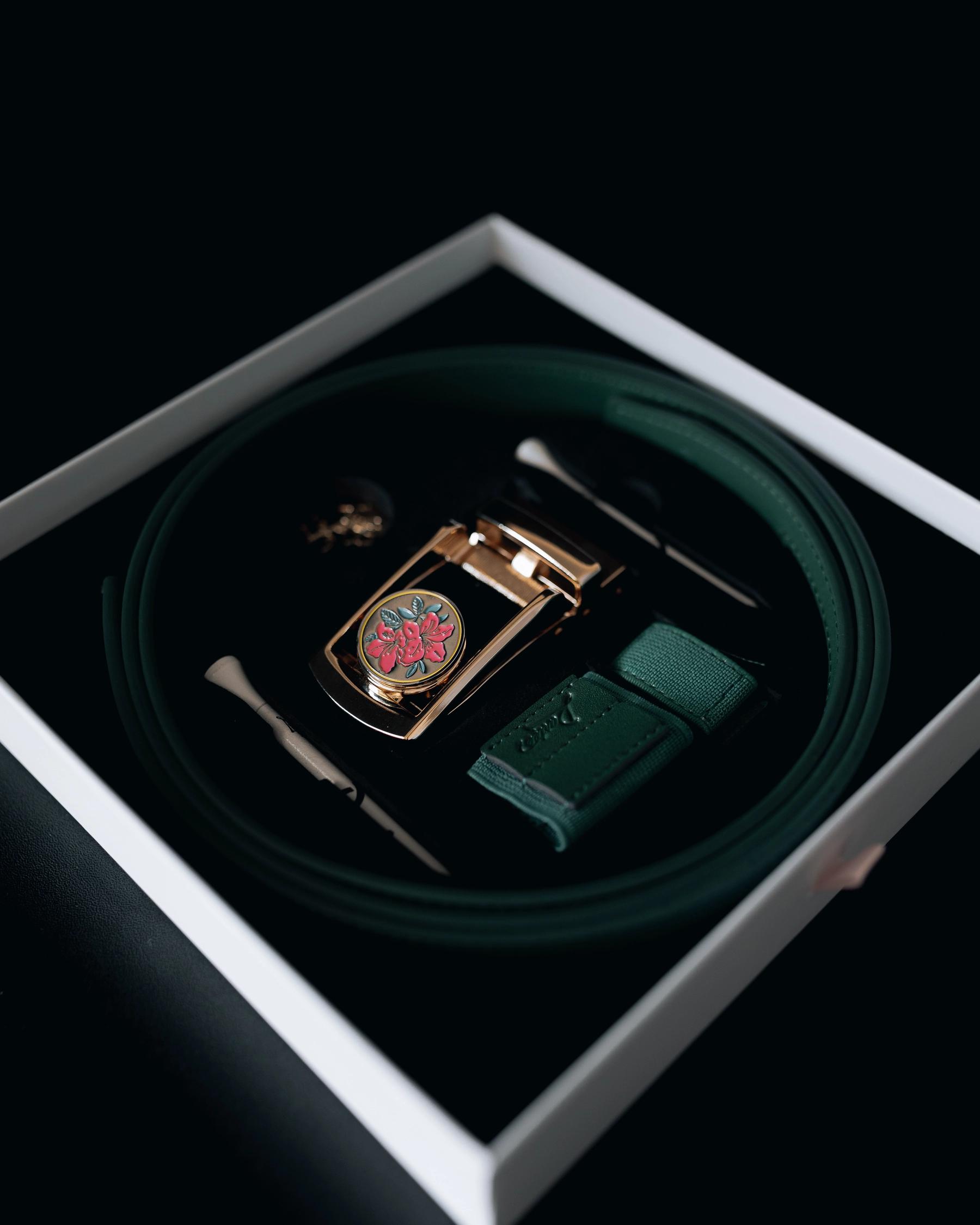 A boxed set containing a green belt with a floral buckle.