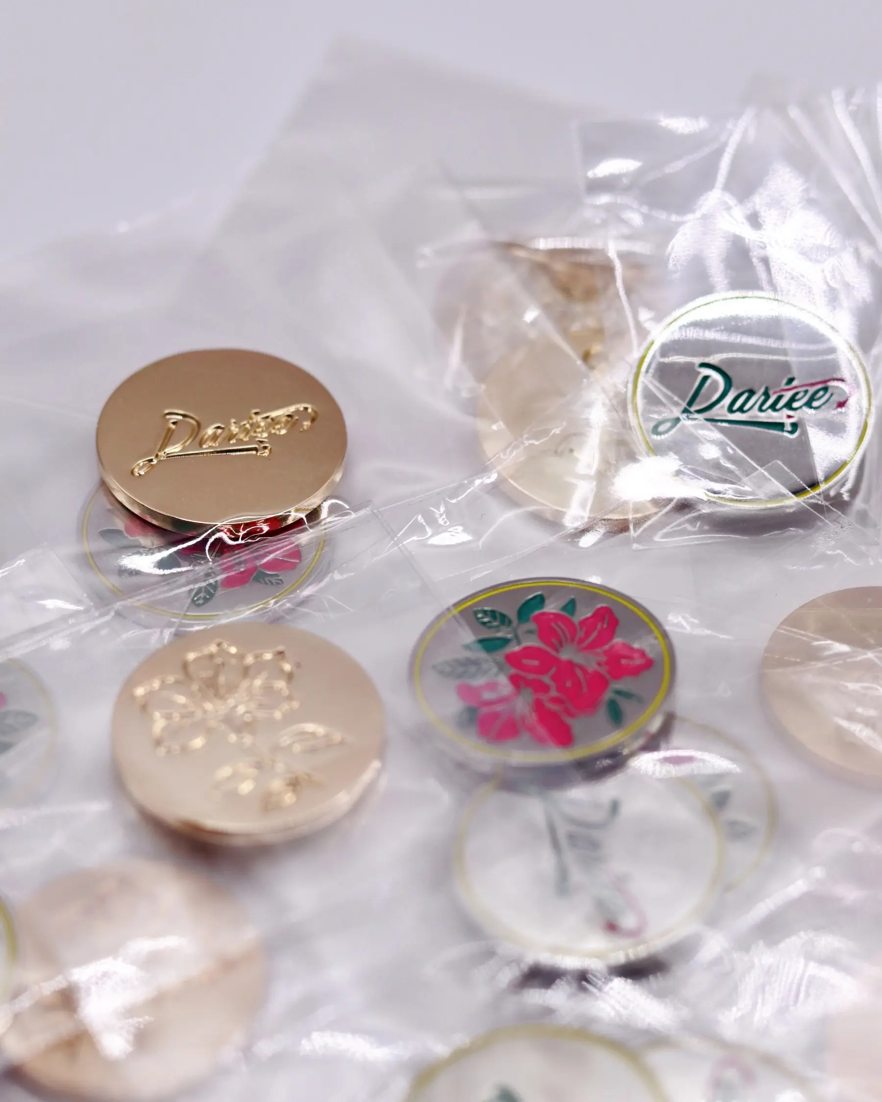 Assorted decorative pins with floral designs and text, in plastic packaging.