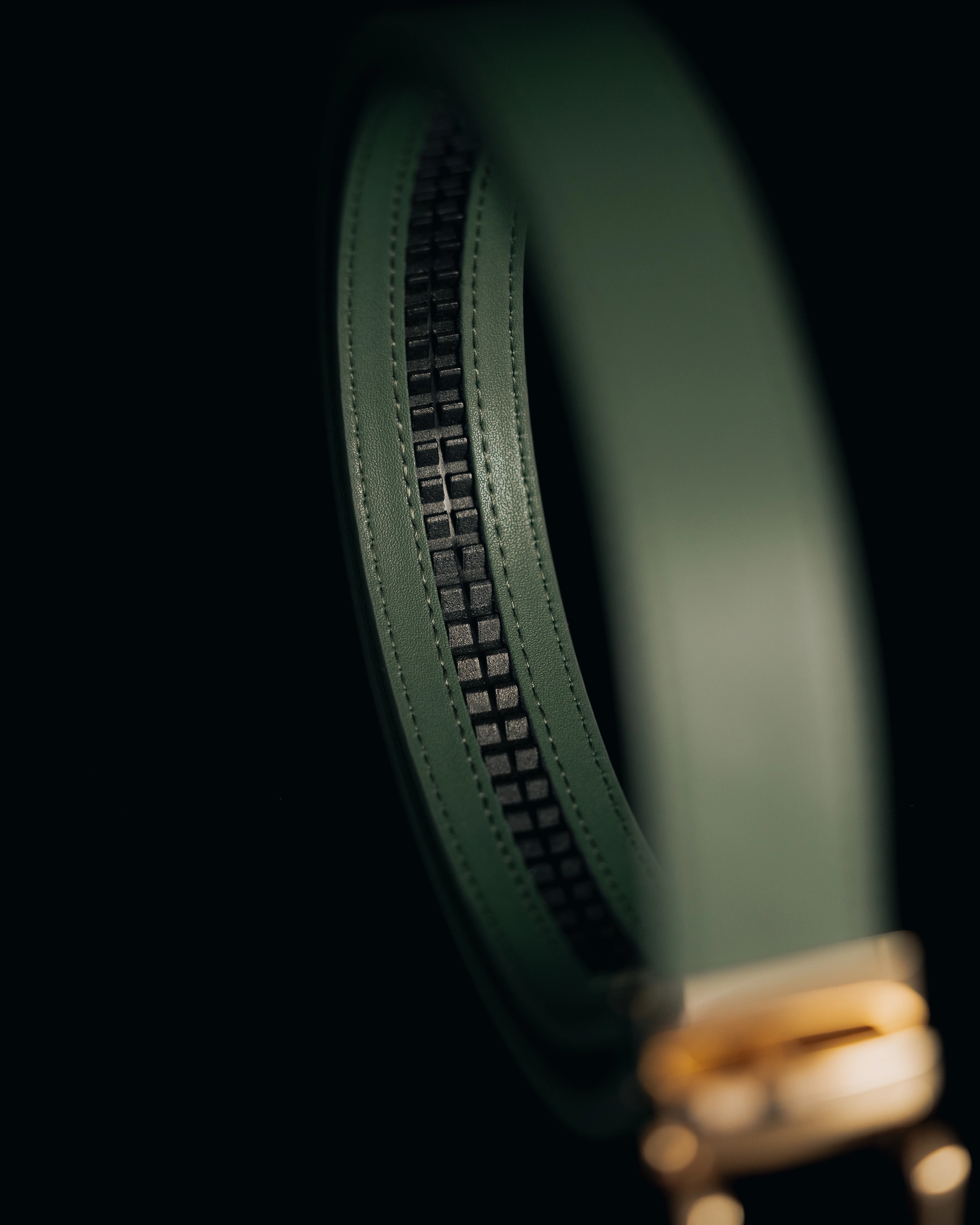 Close-up of a green leather belt with a gold buckle.