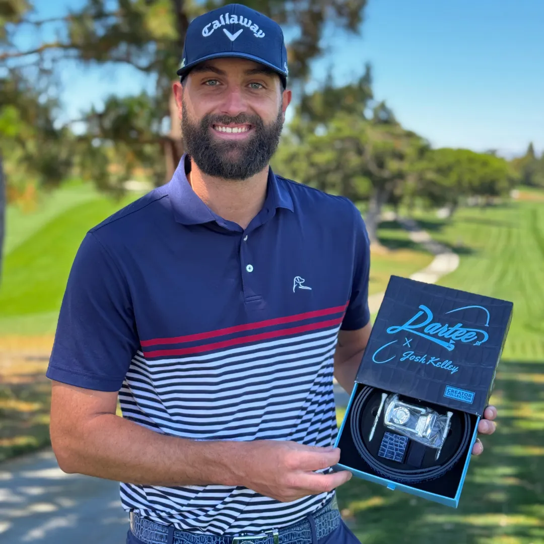 Man holding a branded box on a golf course, wearing a cap and striped shirt.
