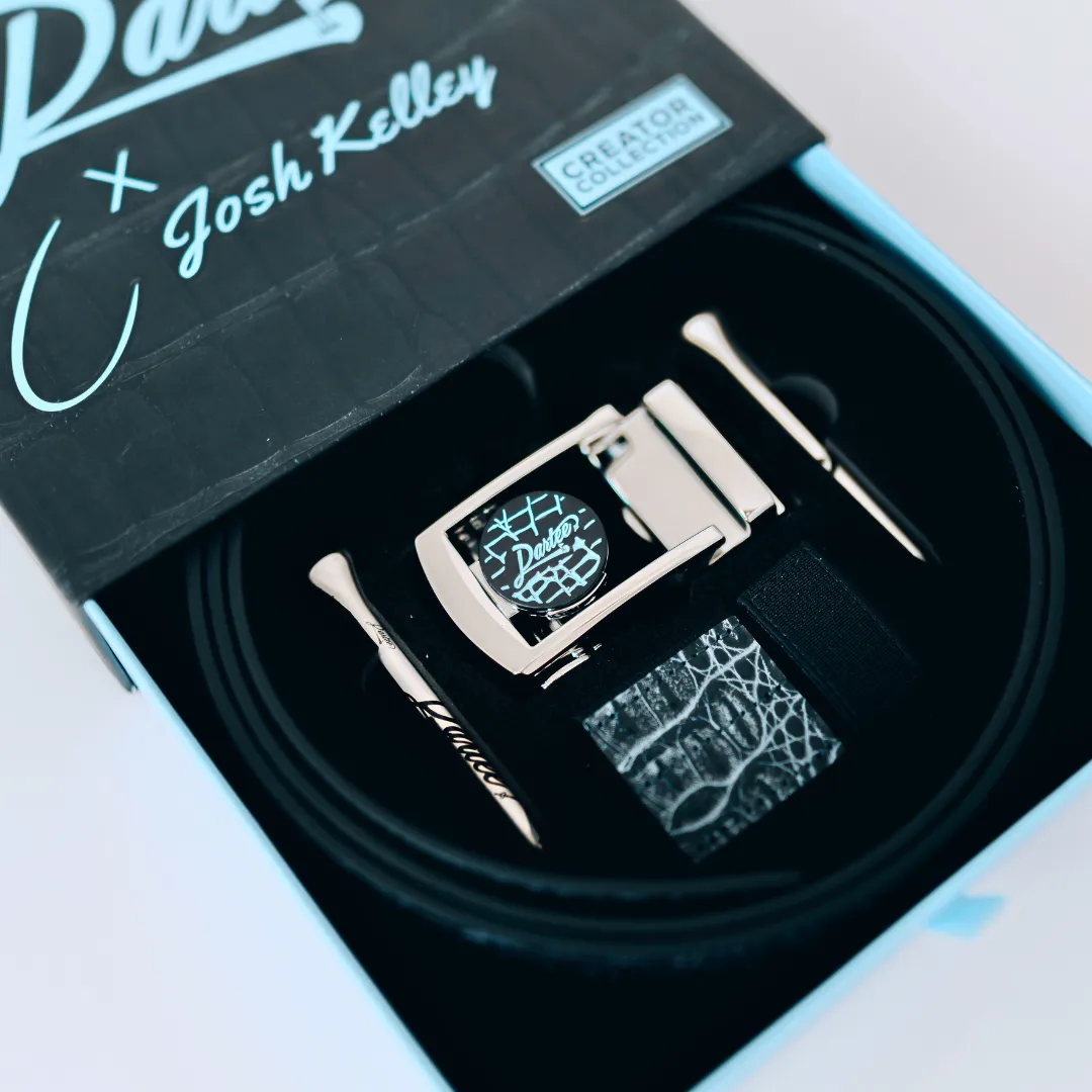A boxed belt with metallic buckle and golf tees inside a designer collection package.