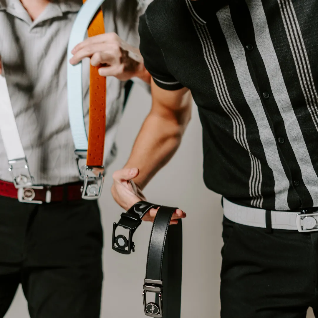 Two people holding belts with unique buckle designs.
