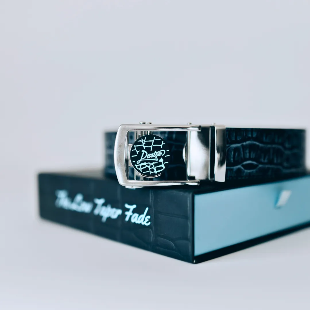Leather belt with a buckle featuring intricate design, placed on a branded box.