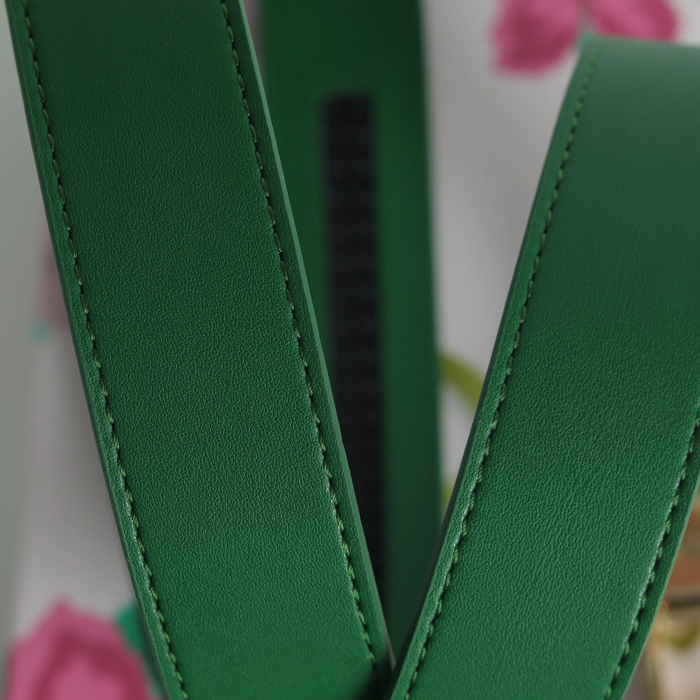 Close-up of green leather straps with pink flowers in the background.