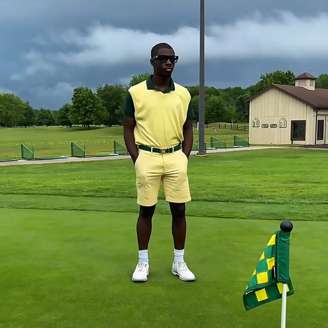 Person in yellow golf attire standing on a golf course near a flag.