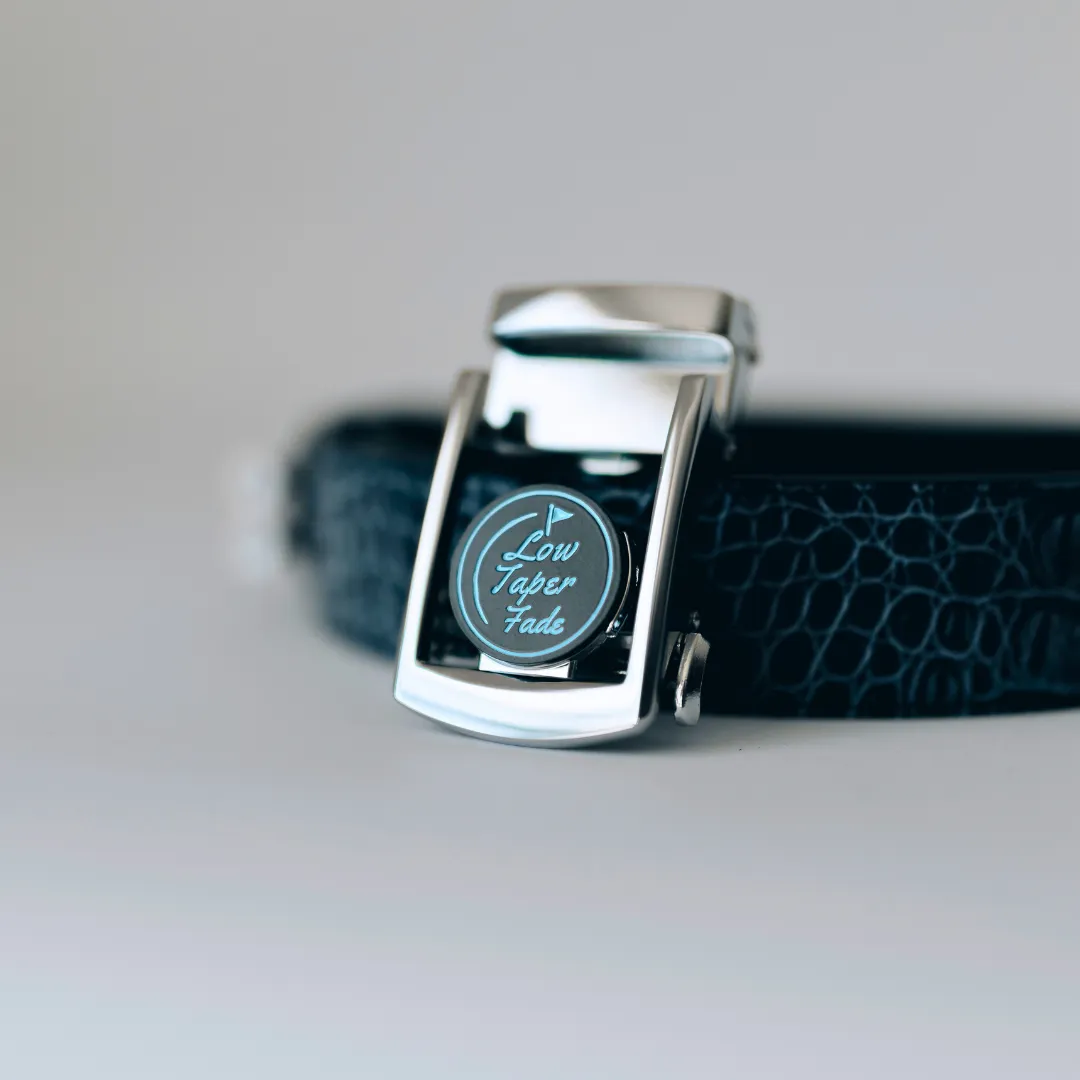 Black leather belt with a metallic buckle featuring the text 'Low Taper Fade.'