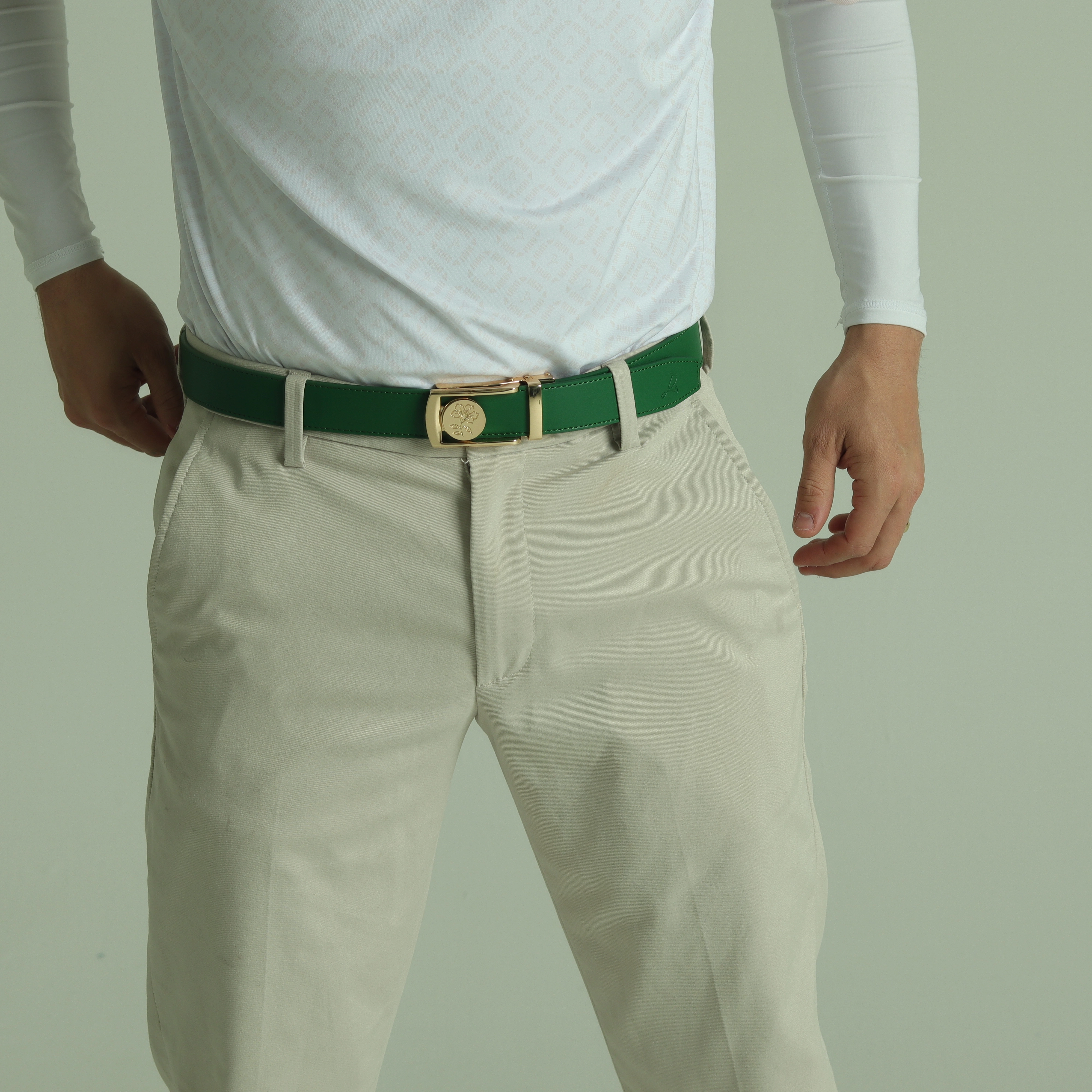 Person wearing white shirt, beige pants, and green belt with gold buckle.
