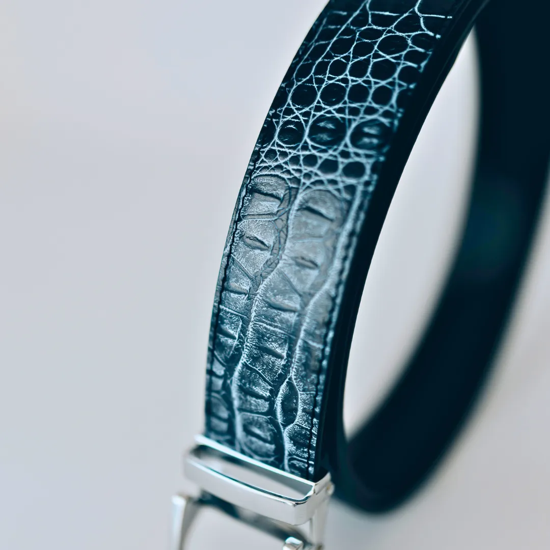 Close-up of a textured black leather belt with a silver buckle.