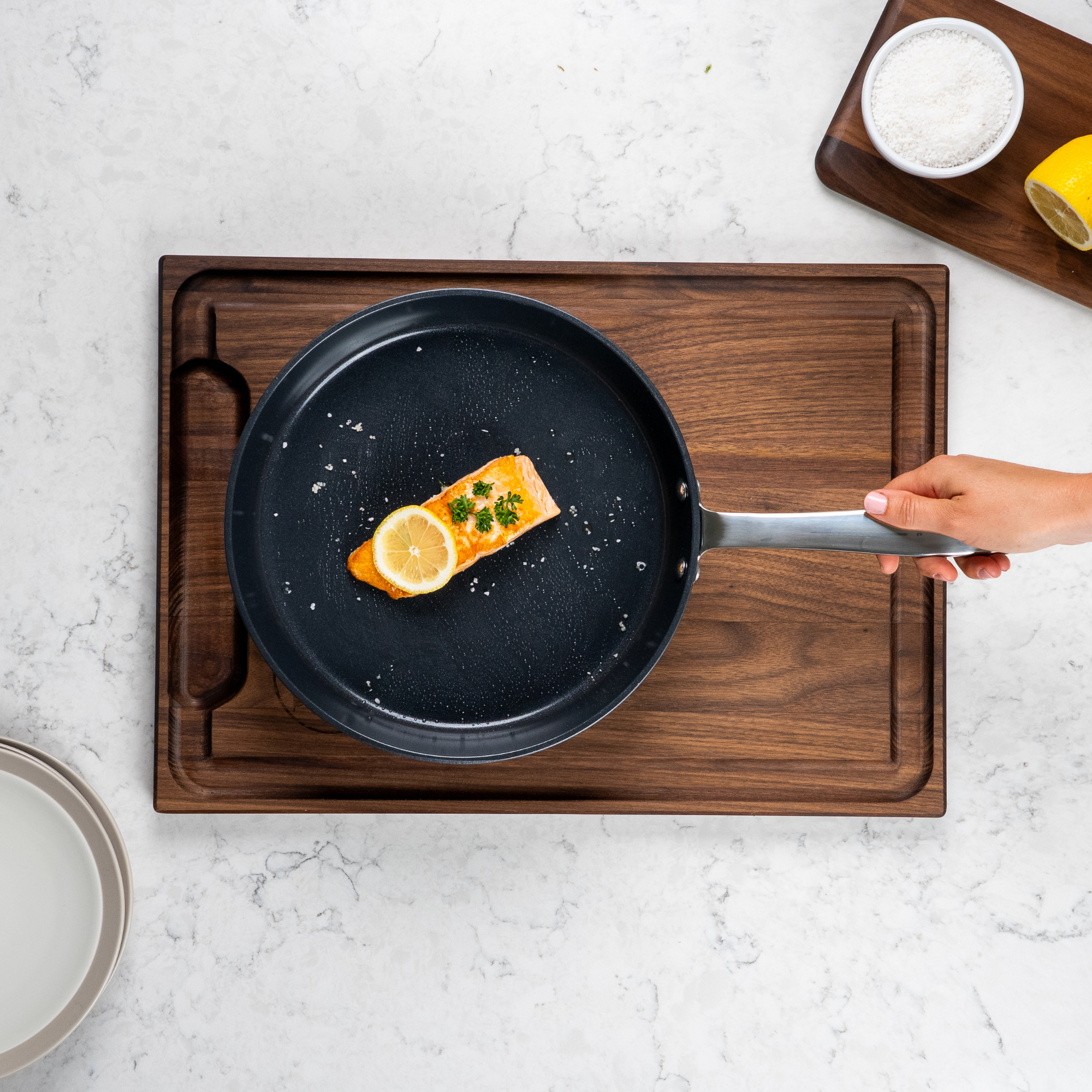 Salmon fillet with lemon and herbs in a frying pan on a wooden board.