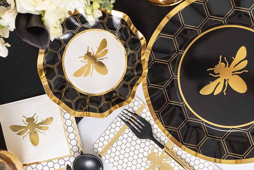 Black and gold bee-themed plates and napkins on a table.