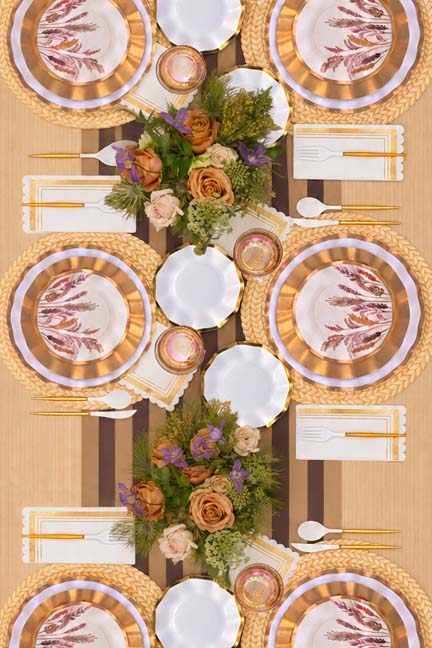An overhead view of a long dining table with elegant place settings, gold cutlery, and floral centerpieces.