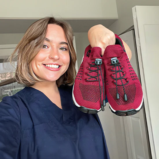 Person smiling and holding a pair of red sneakers.