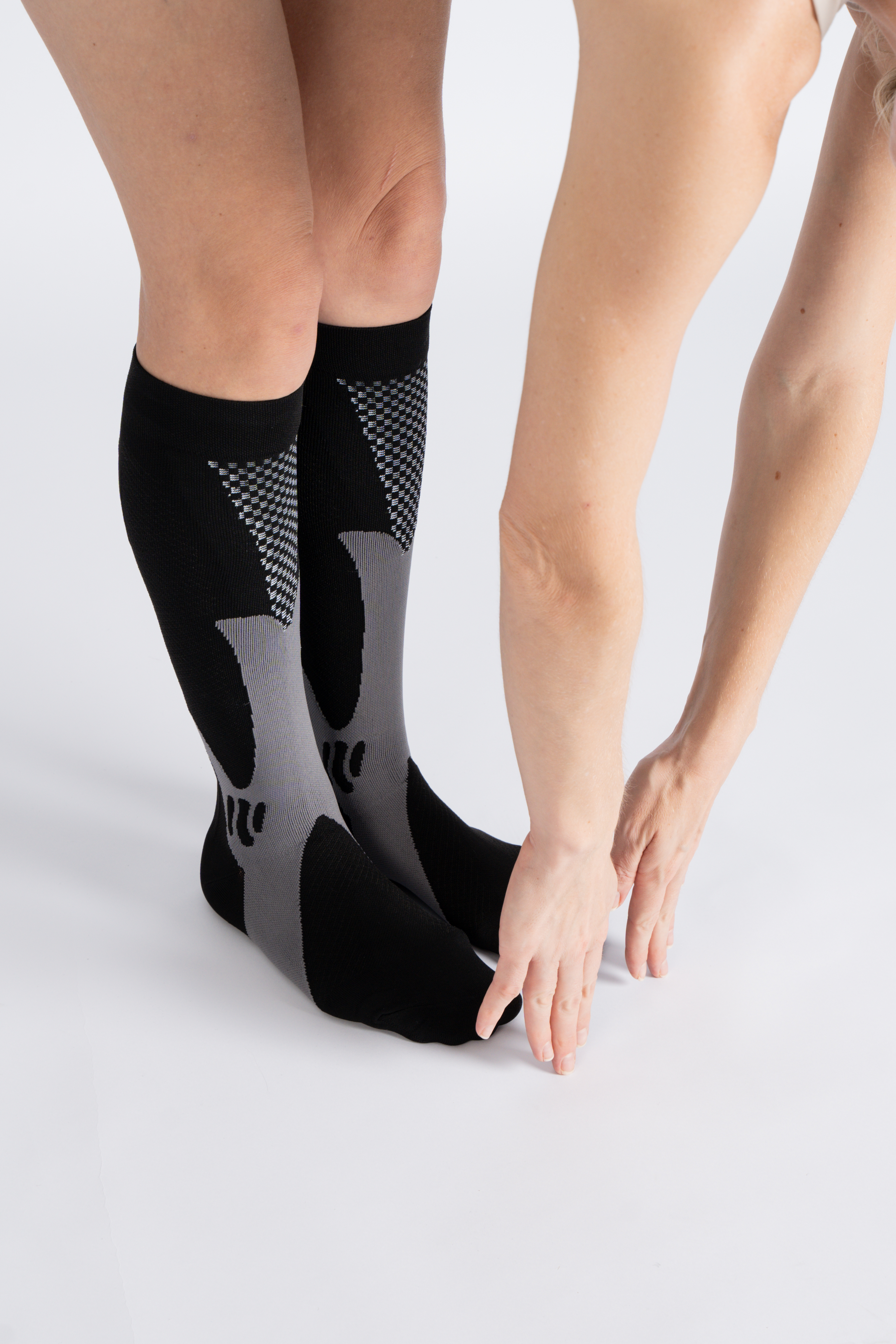 Person wearing black and gray knee-high socks, bending forward.
