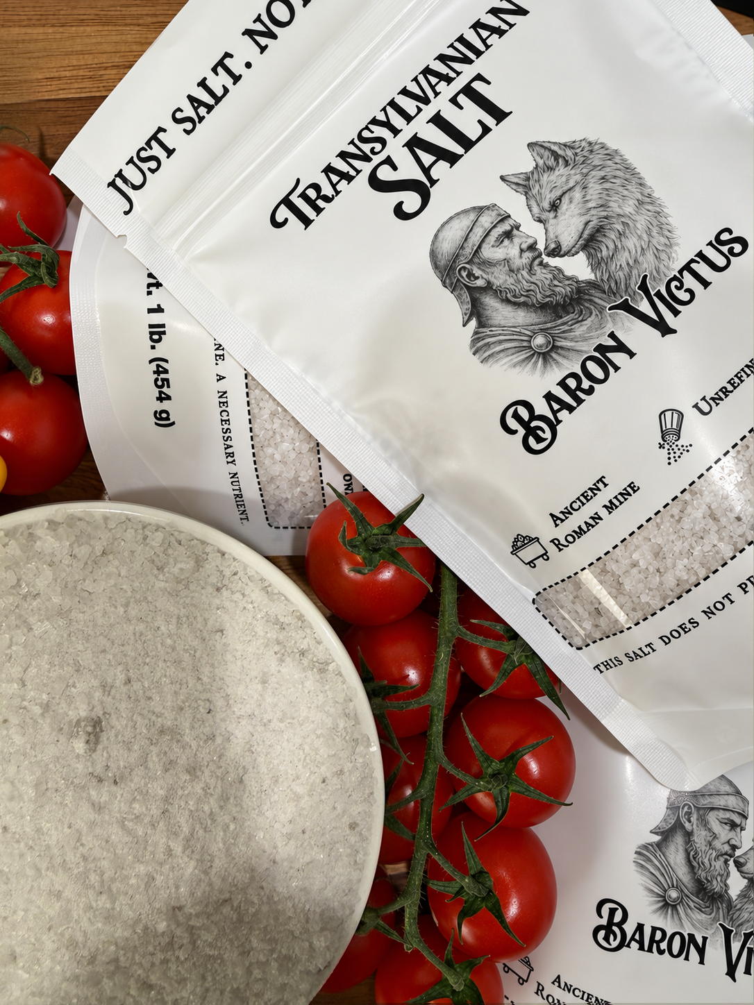 Bags of Transylvanian Salt are arranged with fresh cherry tomatoes and a bowl of coarse salt.