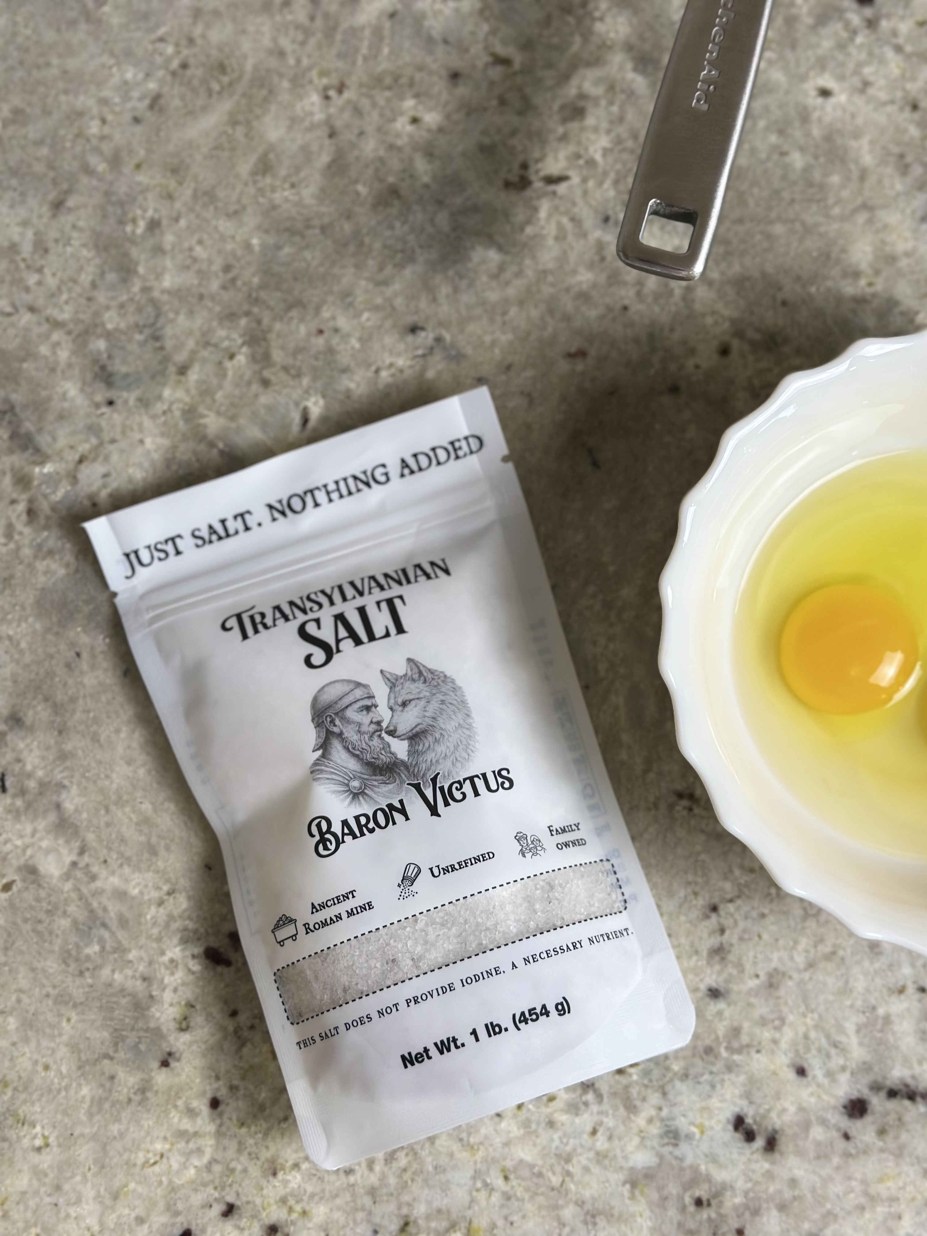 A bag of Transylvanian Salt sits on a countertop next to a white bowl with two eggs.