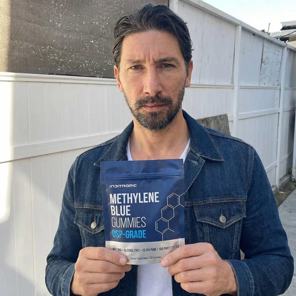 A man in a denim jacket holds a blue pouch of Methylene Blue Gummies.