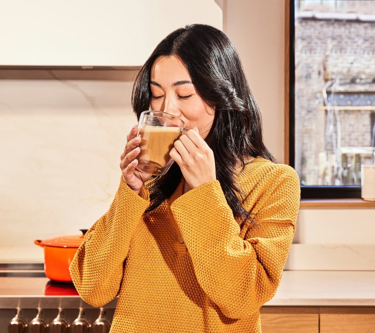 Person smiling while holding a mug in a kitchen setting.
