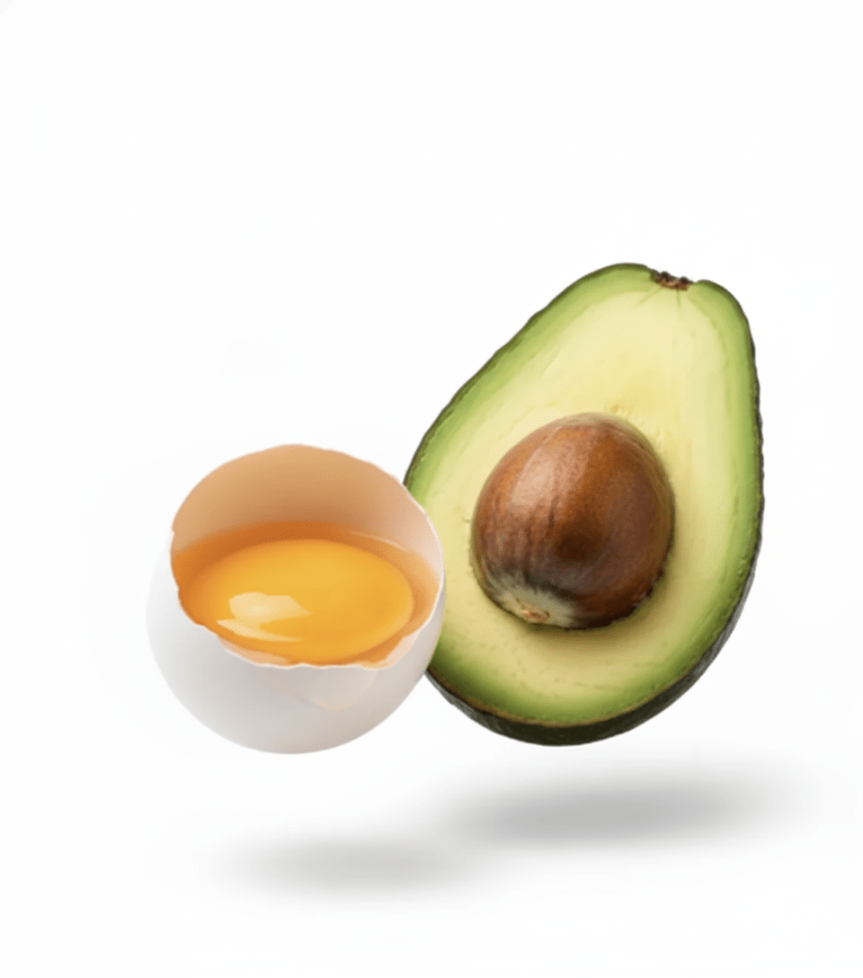 A cracked egg and avocado on a white background.